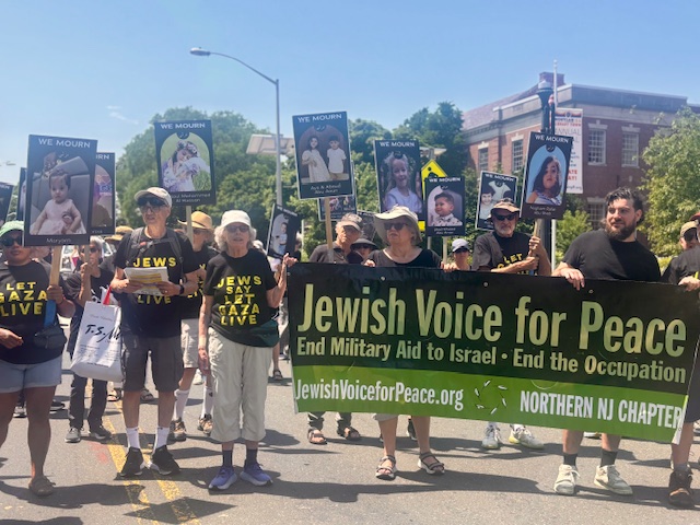 JVPers in “Jews Say Let Gaza Live” T-shirts march behind JVP banner, some holding signs of children, Palestinian and Israel, killed in war.