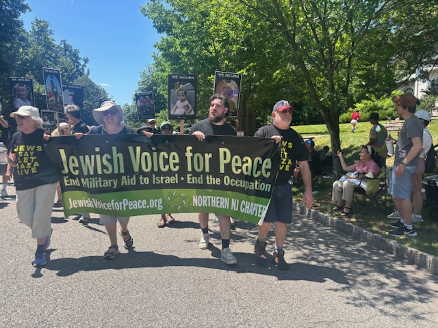 JVPers, some in “Jews Say Let Gaza Live” T-shirts march behind JVP banner as onlookers watch from the curb.
