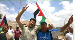 Marchers in Palestine with flags, V for Victory.