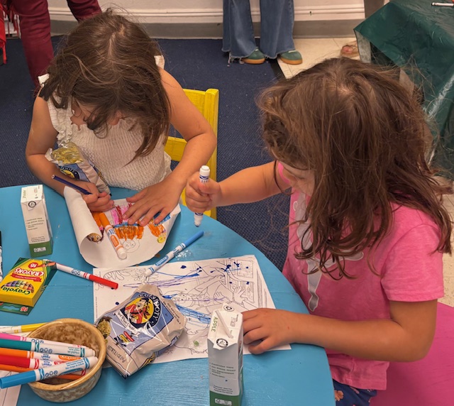 2 young girls color printed pages with markers
