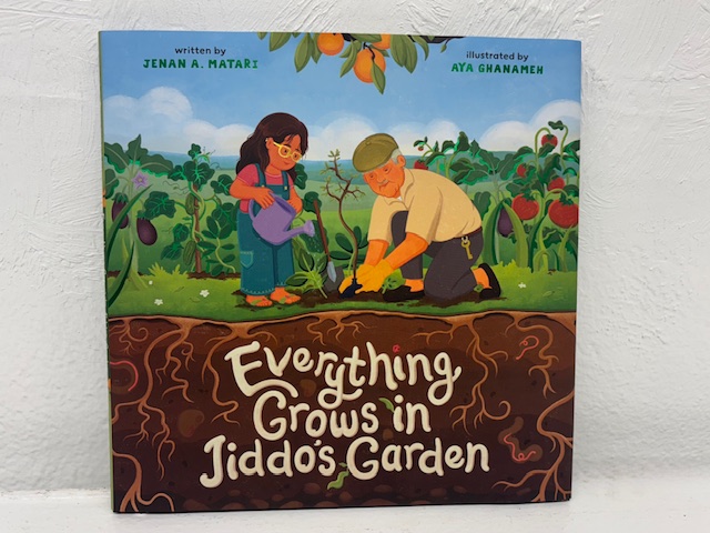 book cover, Everything Grows in Jiddo’s Garden, with girl and grandfather planting a tree, with section of ground and roots visible below them
